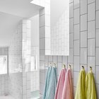 В качестве яркого декора в ванной выступают цветные полотенца, а белые стены выступают в роли нейтрального не надоедающего фона.