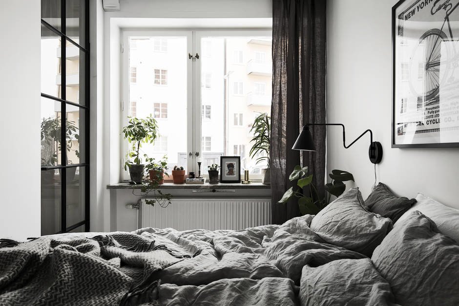 Как и по всей квартире, зеленые растения в спальне довершают образ живой квартиры несмотря на доминирующие белые и серые тона.