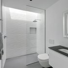 Минималистская белая ванная комната с окном над душем.