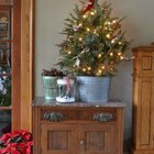 Еще одна небольшая елка в цинковом ведре украшенная новогодними огоньками.