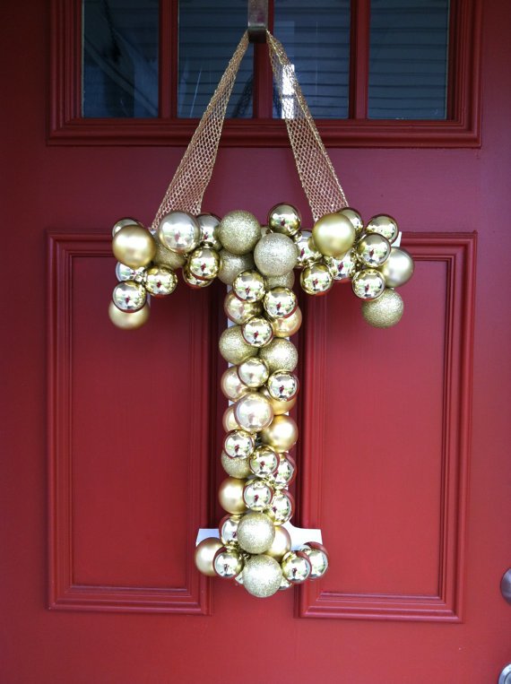 Рождественский венок из елочных игрушек на двери дома в виде монограммы.