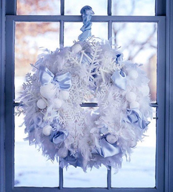 Рождественский венок из снежинок, белых шерстяных шариков и лент украшает окно.