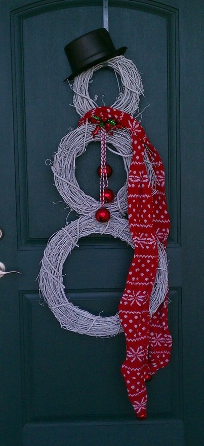 Венки из белой крашенной виноградной лозы в виде снеговика в котелке и с красным шарфом на входной двери.