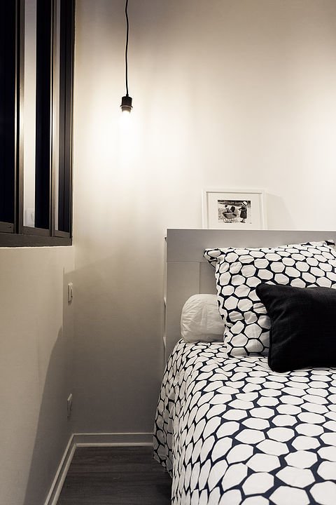 Спальня выполнена в сдержанных черно-белых тонах. Если присмотреться, то над изголовьем кровати можно заметить полку, а также полочки сбоку изголовья.