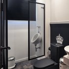 Ванная комната в черно-белых тонах с королевским черным унитазом и выделенный стальными решетчатыми воротами писсуар.