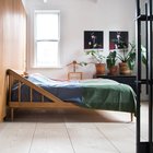 Деревянная кровать с необычным, но весьма привлекательным изголовьем. Целую стену спальни занимает система хранения с деревянным фасадом.