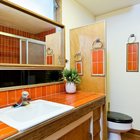 Ванная комната рядом с одной из спален украшена красным кафелем, как и кухня.