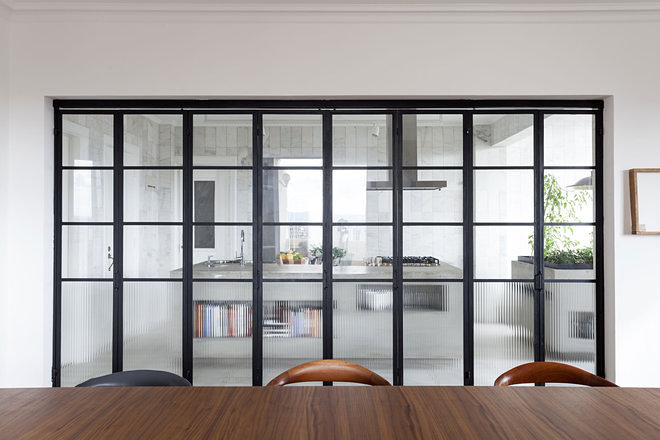 Перегородка из стекла и металла между кухней и столовой очень соответствует атмосфере квартиры